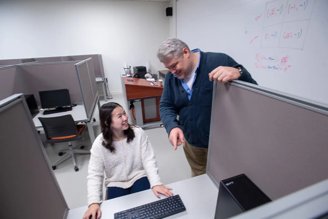 A faculty member helps a student with research in the Experimental Economics Lab