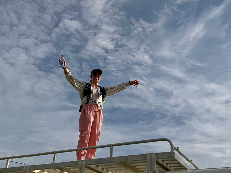 Faculty member on top of bus, arms spread, during safari in Mole National Park
