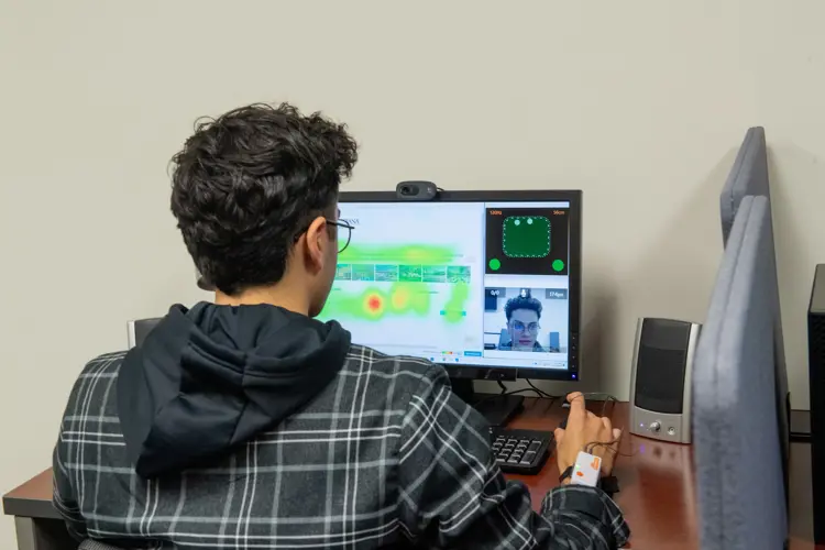 A student does screen-based eye-tracking research in the Biometrix Discovery Lab