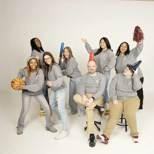 Area Coordinators play with athletic props and make silly in the photo studio for their informal group photo.