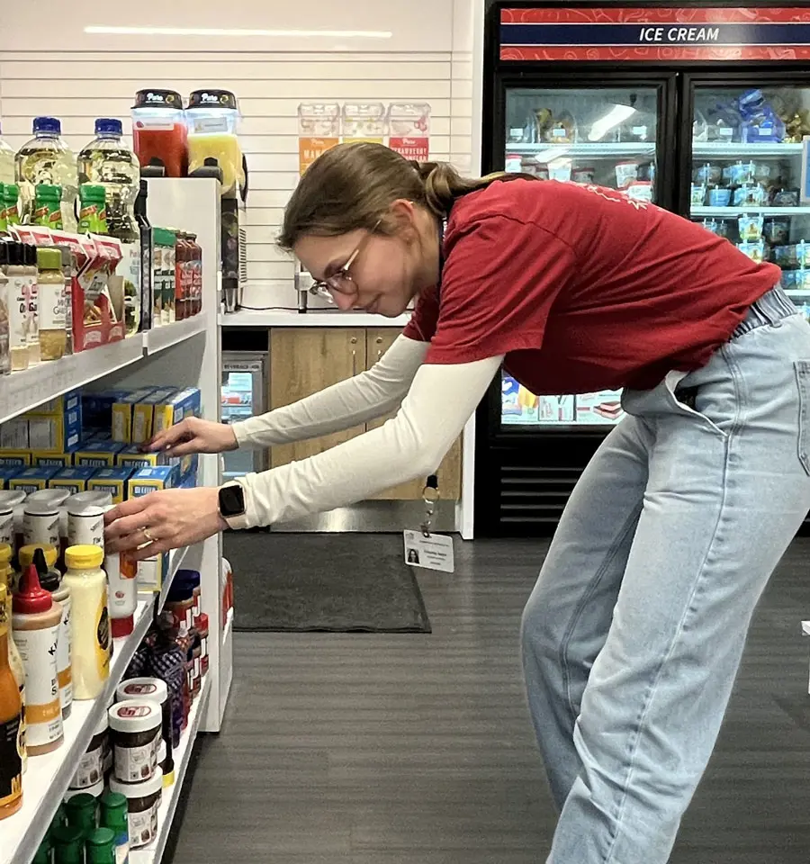 Student picking up food from the C store shelf